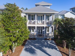 A two-story house with a covered front porch, a balcony on the second floor, and a driveway leading to the entrance. - 100 FIVE STAR REVIEWS!   Rhapsody in Blue... Second home, not just a rental!  (Panama City Beach)