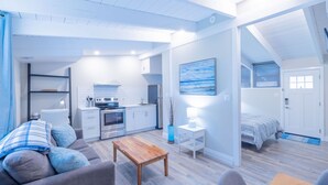 Una sala de estar moderna y bien iluminada, con un sofá, una mesa de centro y una kitchenette.