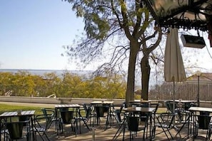 Une terrasse extérieure avec des tables et des chaises, une pergola et une vue sur la mer.
