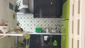 A compact kitchen with dark cabinets, a green refrigerator, and a patterned backsplash.