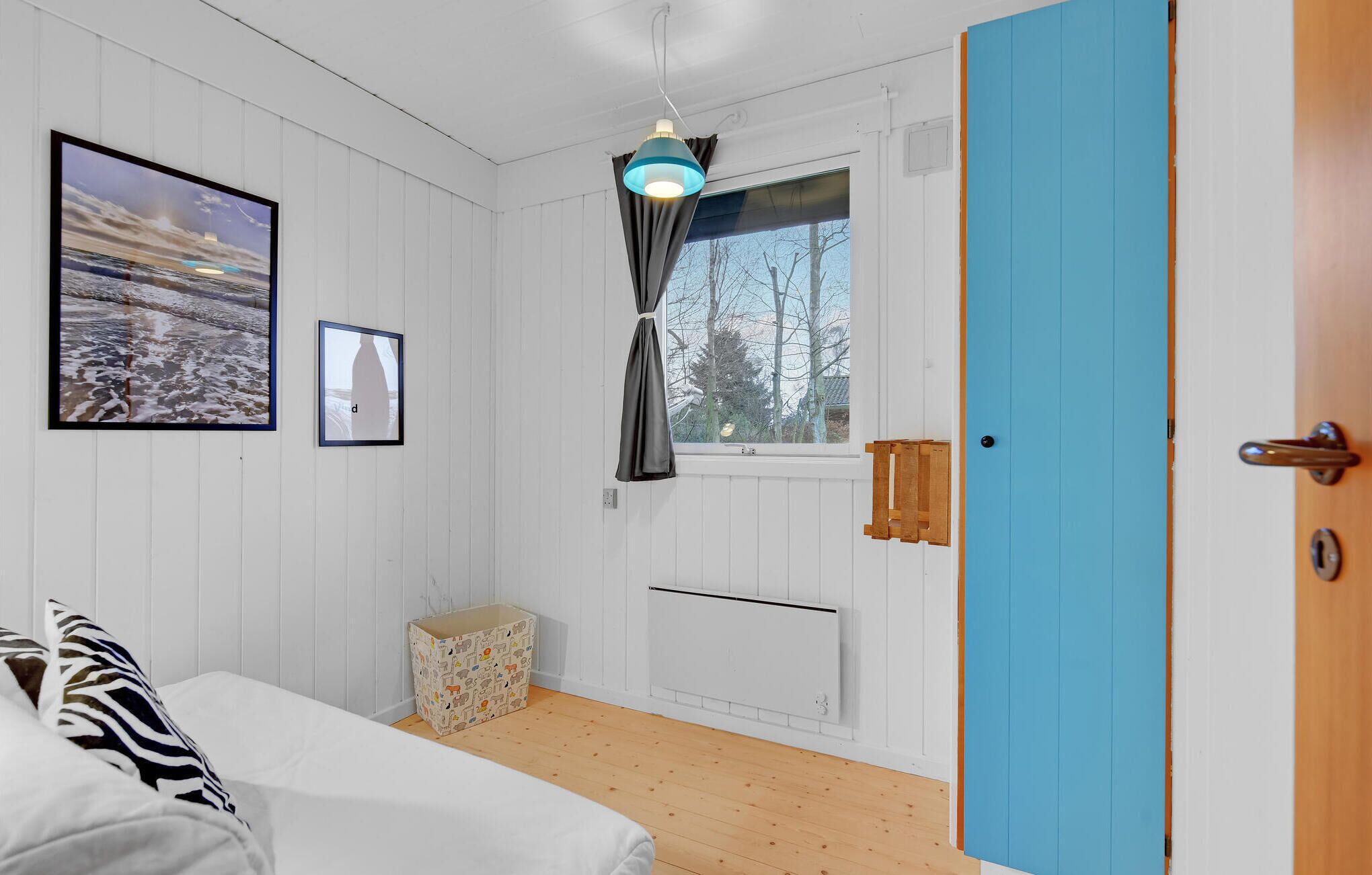Een slaapkamer met een bed, een raam met gordijnen, een radiator en een deur.