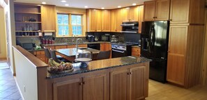 Enjoy cooking in this well-equipped kitchen with a refrigerator, stove, and microwave, plus a convenient island with a sink and a bowl of fresh fruit.