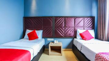 A hotel room with two beds, a nightstand with a phone, and a blue wall.