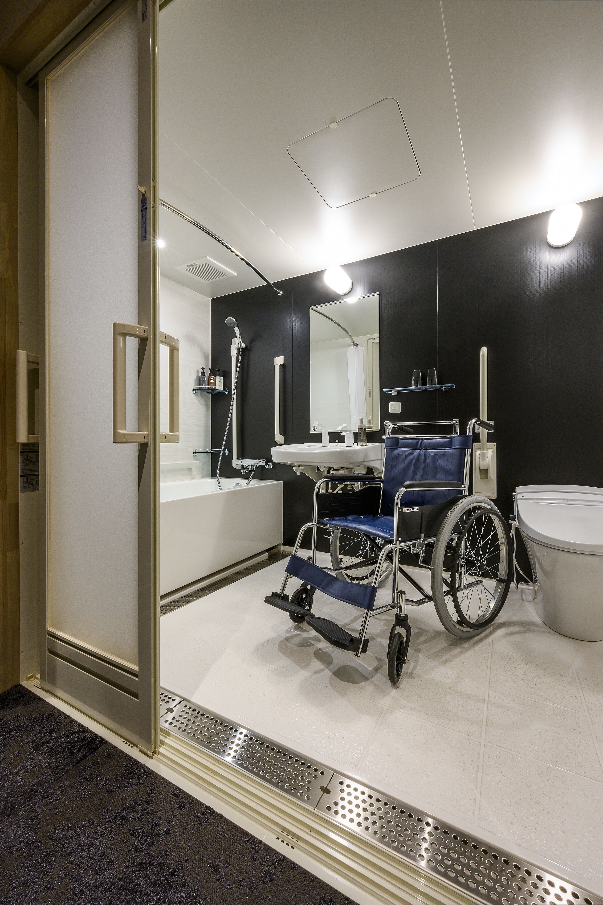 Ein modernes Badezimmer mit Rollstuhl, großem Spiegel und Badewanne.