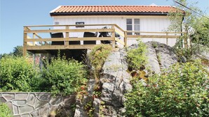 Un edificio blanco con techo de tejas rojas y terraza de madera.