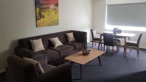 Una sala de estar con sofá, mesa de centro y comedor con sillas y mesa.
