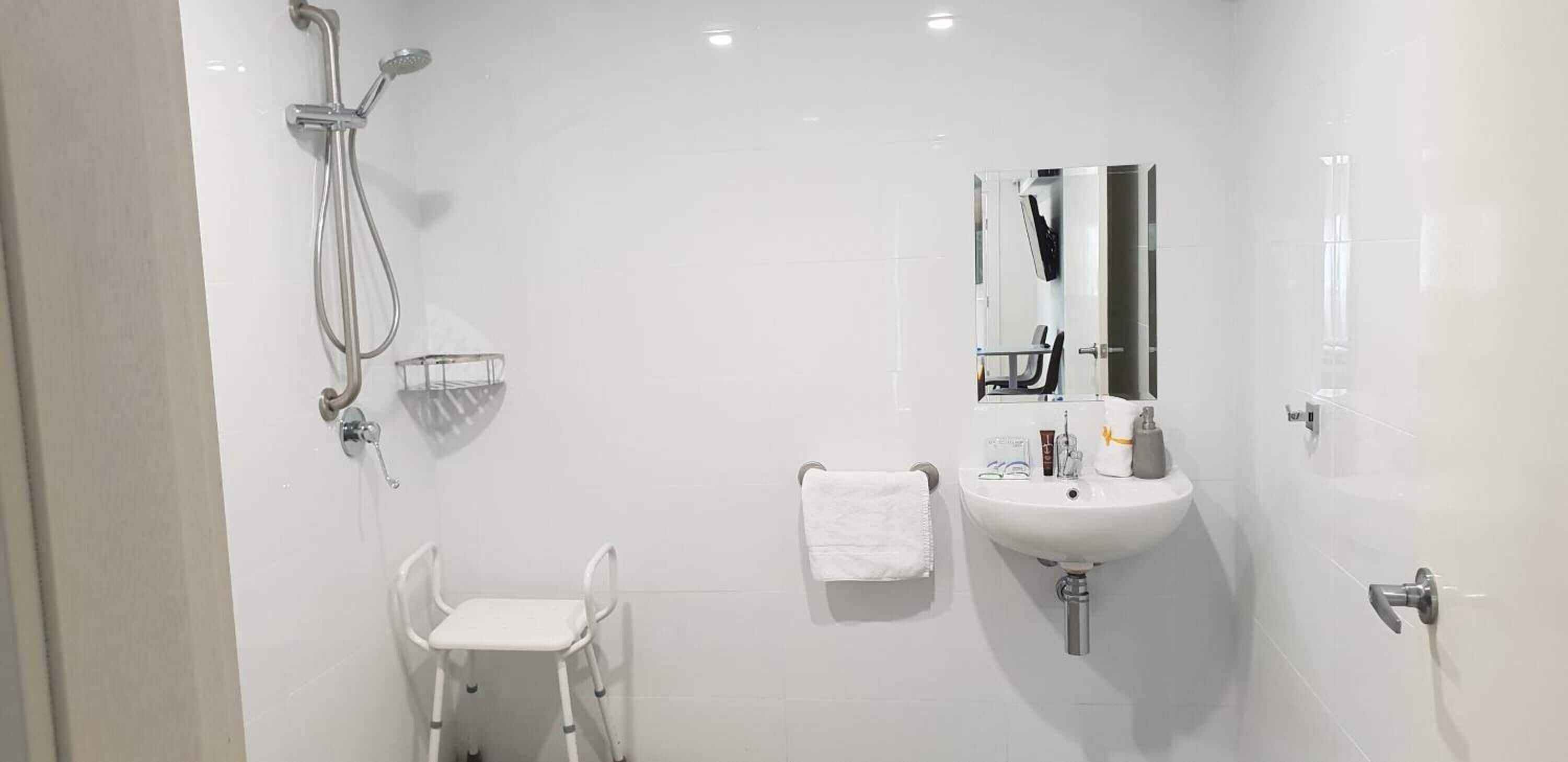 A modern bathroom with a white sink, mirror, and shower.