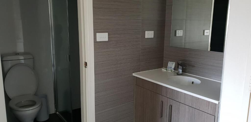 A bathroom with a toilet, a glass shower enclosure, a sink, and a mirror.