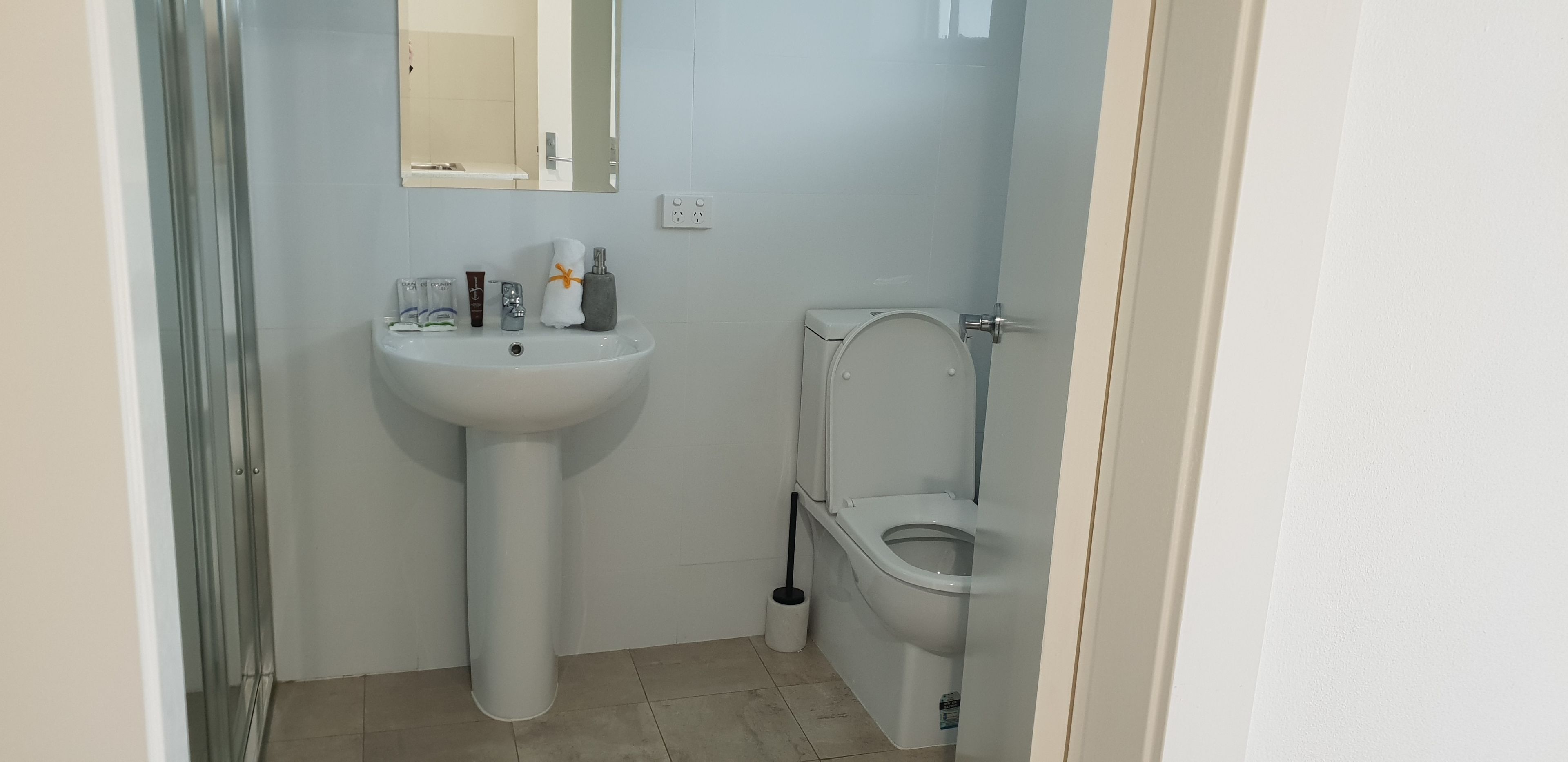 Ein kleines Badezimmer mit einem weißen Waschbecken, einer Toilette und einem Spiegel über dem Waschbecken.