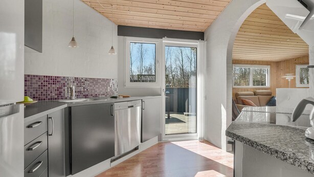 A modern kitchen with stainless steel appliances, a tiled backsplash, and a wooden ceiling.