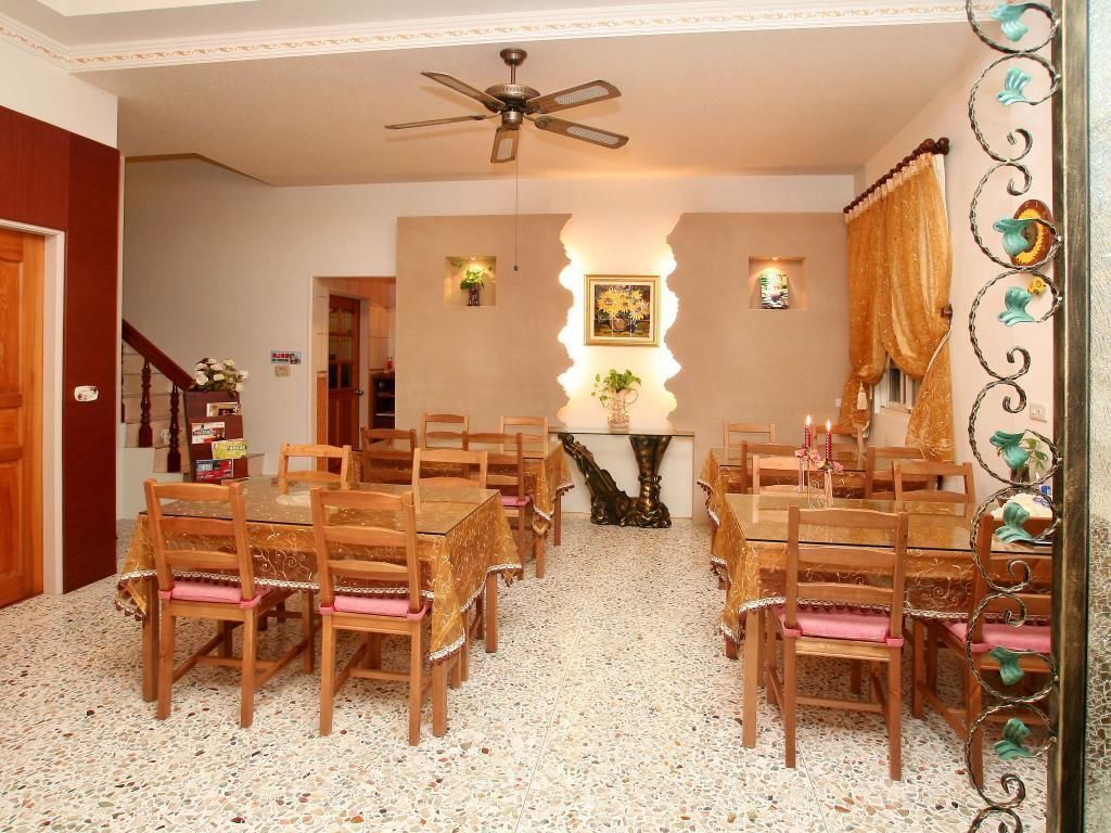 A dining area with wooden tables and chairs, a ceiling fan, and a decorative wall with a framed picture.