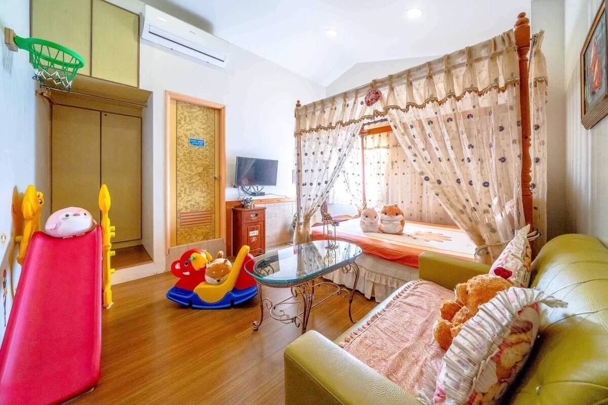 A cozy living room with a sofa, a small table, a television, and a window with curtains.