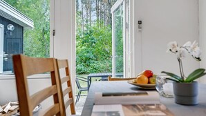 Zona pranzo con una sedia di legno, un tavolo con un piatto di frutta, un'orchidea in vaso e un libro.