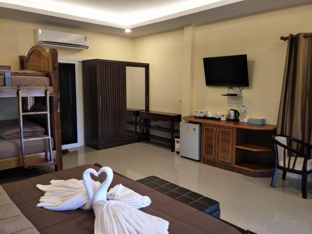 A hotel room with a bed, a TV, a desk, a chair, and a small kitchenette.