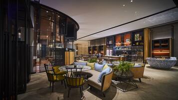 A modern lounge area with round tables, yellow chairs, and a large seating area with sofas.