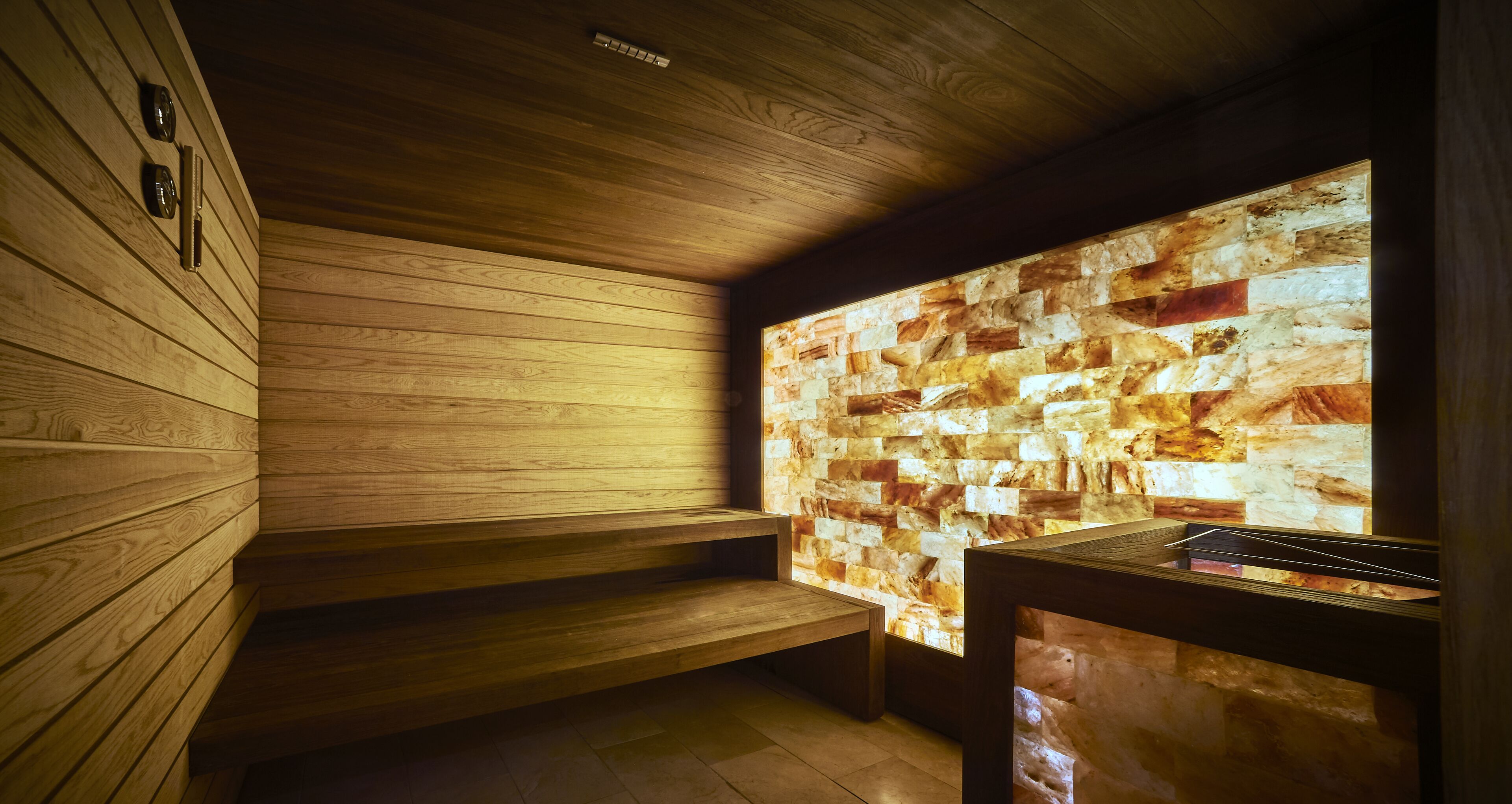 A sauna with wooden benches and a stone wall.