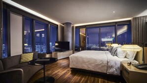 A modern hotel room with a large bed, a sofa, a TV, and a city view. - EQ Kuala Lumpur (Kuala Lumpur)