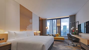 A hotel room with a large bed, a desk, a chair, and a view of the city skyline.