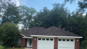 A single-story house with a garage, surrounded by a well-maintained lawn and trees. - Foley. 20 mins to beaches, close to Tanger Outlet, Owa, sports complex (Foley)