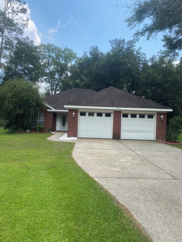 A single-story house with a garage, surrounded by a well-maintained lawn and trees. - Foley. 20 mins to beaches, close to Tanger Outlet, Owa, sports complex (Foley)