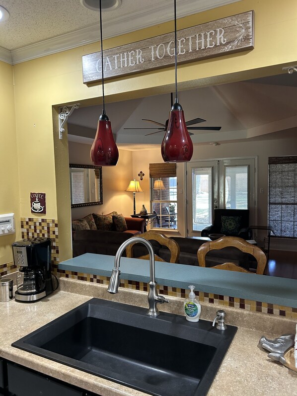 Enjoy a homey atmosphere in this well-appointed room, featuring a modern kitchen area with a large sink, coffee maker, and cozy seating area.
