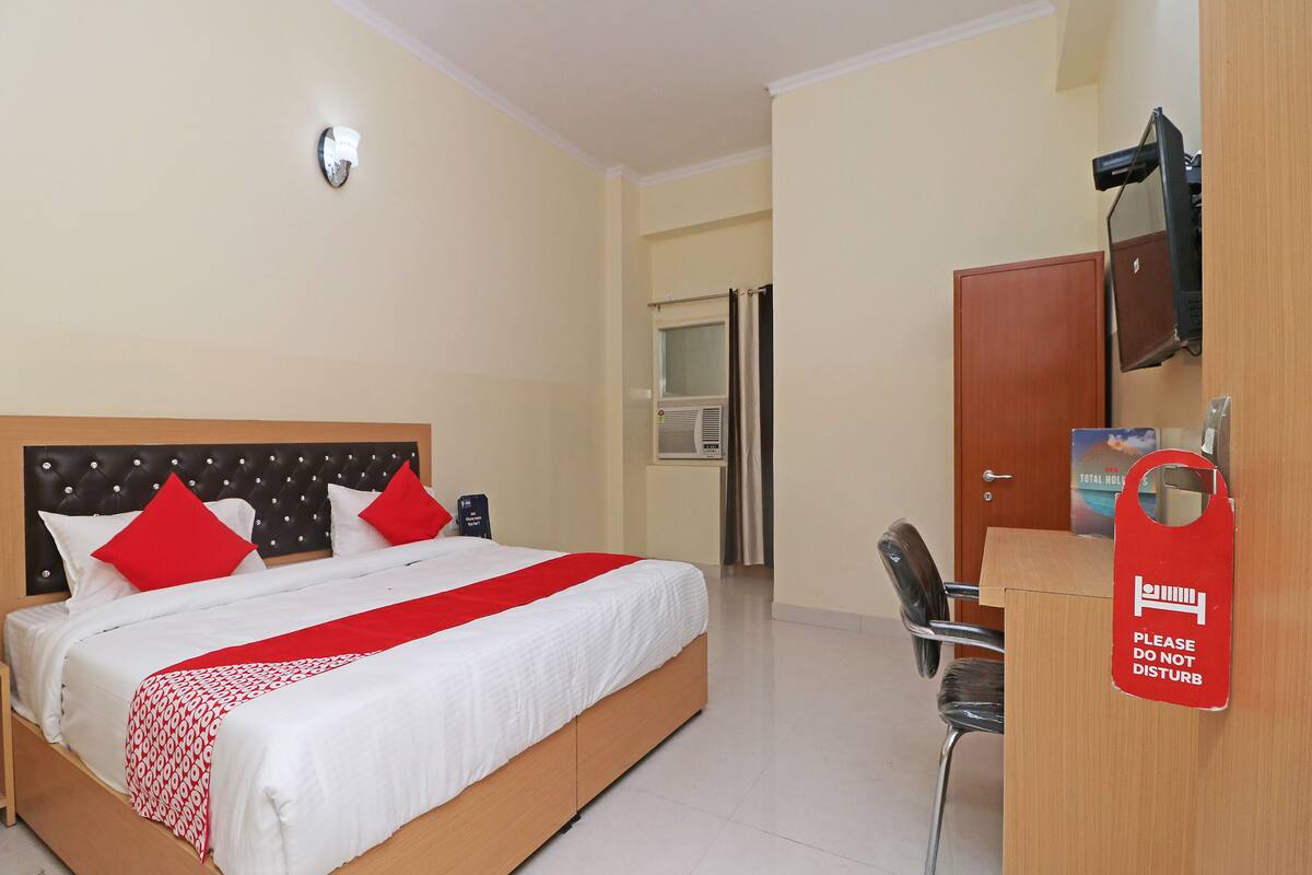 Une chambre d’hôtel avec un lit, un bureau, une chaise, une télévision et une porte.