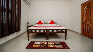 A room with a double bed, a wooden door, and a patterned rug. - OYO 18272 Hotel Lambodar (Pushkar)