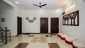 A hallway with a ceiling fan, patterned floor tiles, and a wall-mounted artwork. - OYO 18272 Hotel Lambodar (Pushkar)