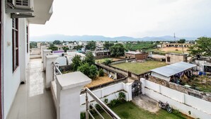 A residential area with a view of distant mountains, a gated compound, and a parked motorcycle. - OYO 18272 Hotel Lambodar (Pushkar)