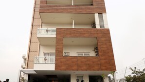 A multi-story building with a modern design, featuring balconies and large windows. - OYO 28616 Hotel New View (Gurugram)