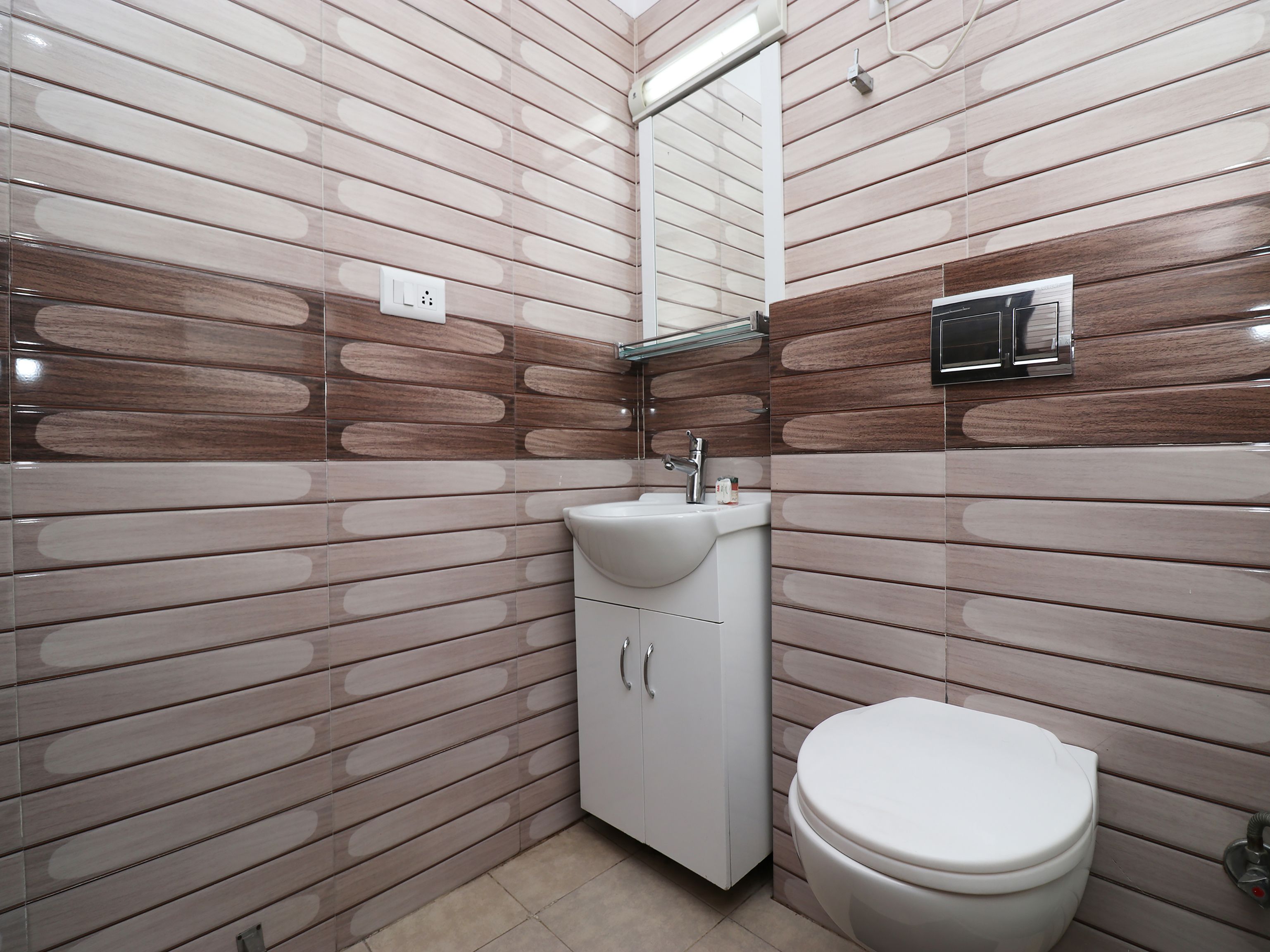 A bathroom with a modern design, featuring a sink, toilet, and cabinet.