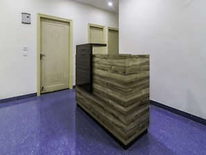 A reception area with a wooden reception desk, a door, and a light switch on the wall.