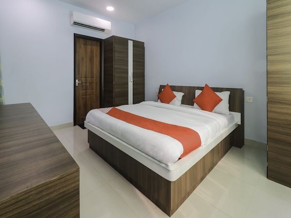 A bedroom with a bed, wooden wardrobe, and an air conditioning unit.