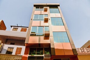 Un edificio de varios pisos con un diseño arquitectónico moderno, que cuenta con amplios ventanales y unidades de aire acondicionado.