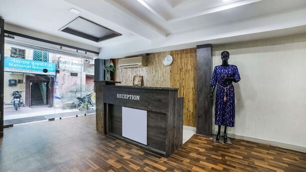 A reception desk labeled "RECEPTION" with a clock above it, a mannequin in a blue dress, and a sign for "National Insurance" visible through the window. - OYO 28783 Hotel Vaishali (Ajmer)