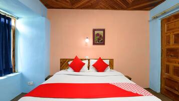 A bedroom with a wooden ceiling, a bed with white and red bedding, a window with curtains, and a wooden door.
