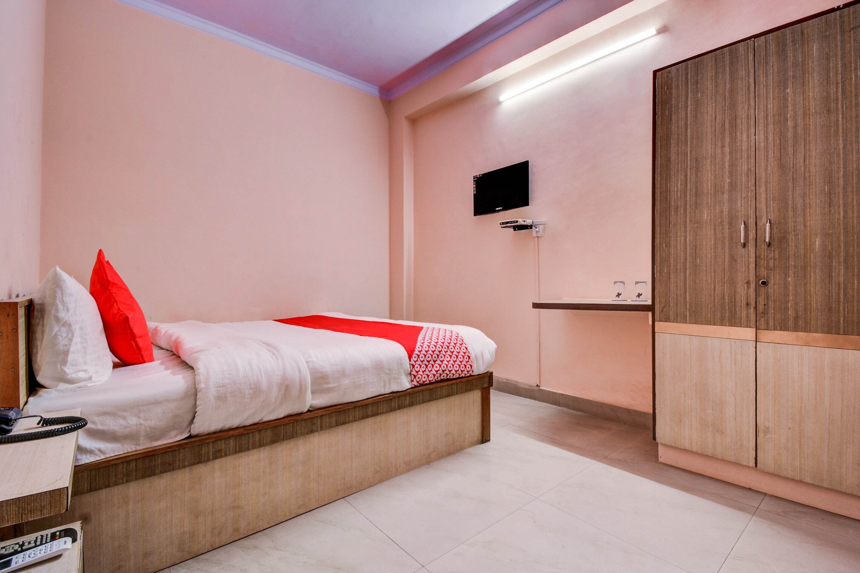 A bedroom with a bed, a wardrobe, a TV, and a bedside table.