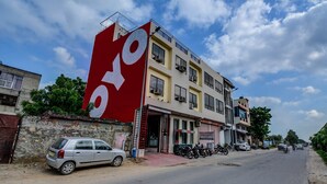 A building with a large red sign, a parked car, and a motorcycle.