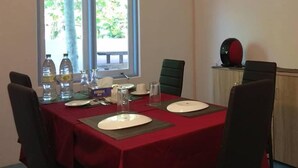 A dining area with a table set for four, two water bottles, a box of tissues, and a red tablecloth. - Veyvah Inn Maldives (Veyvah)