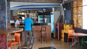 Zona de bar con taburetes, mostrador y estantes llenos de botellas.
