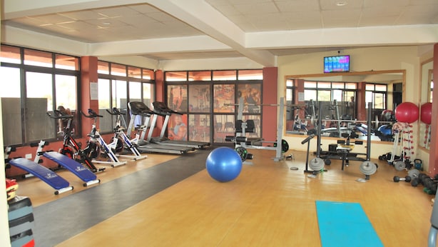 Un gimnasio con cintas de correr, bicicletas estáticas, pesas y pelotas de ejercicios.