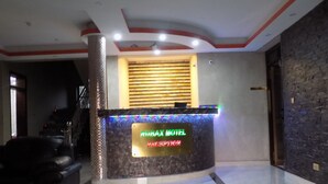 A reception area with a marble floor, a reception desk, and a wall with a textured pattern. - Rubax Motel (Mbarara)