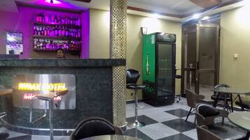 A hotel lobby with a bar area, a Heineken refrigerator, and check-in counters.