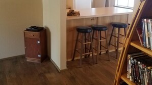 A compact living space with a kitchen area, a bookshelf, and a flat-screen TV mounted on the wall. - Little Red Cabin in the woods (Nordman)
