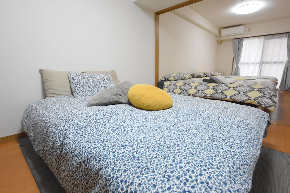 Een hotelkamer met twee bedden, elk met beddengoed en kussens met een patroon.