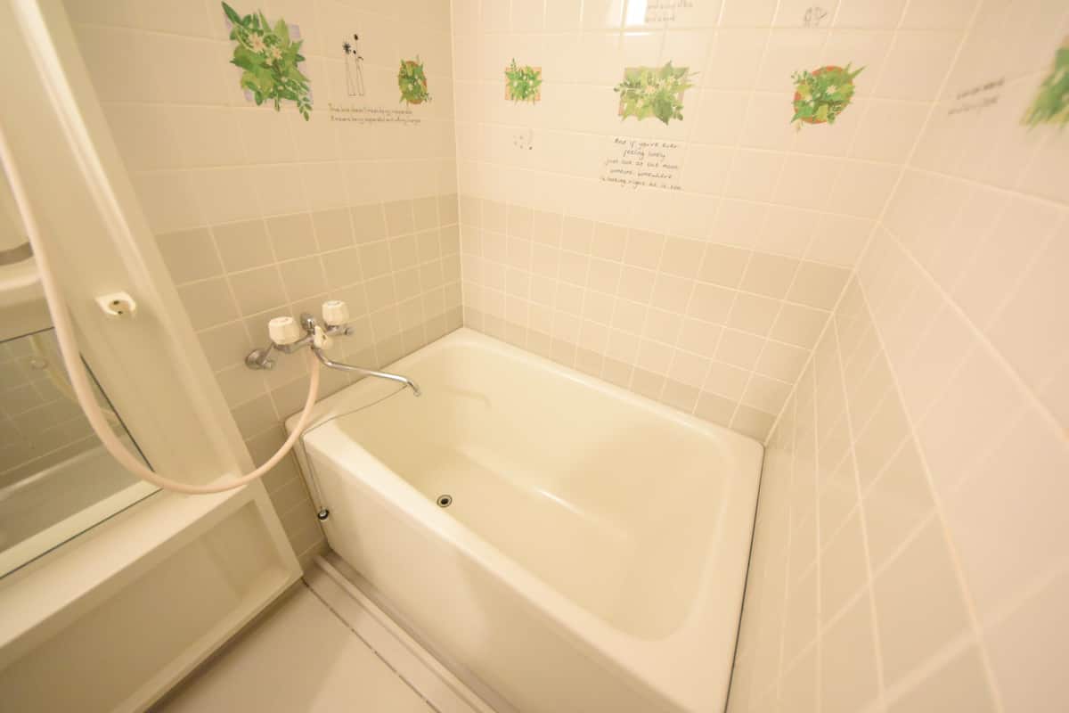Een badkamer met een bad, douche en toilet.