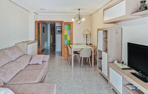 Ein Wohnzimmer mit einer Couch, einem Fernseher und einem Essbereich mit Stühlen und einem Tisch.