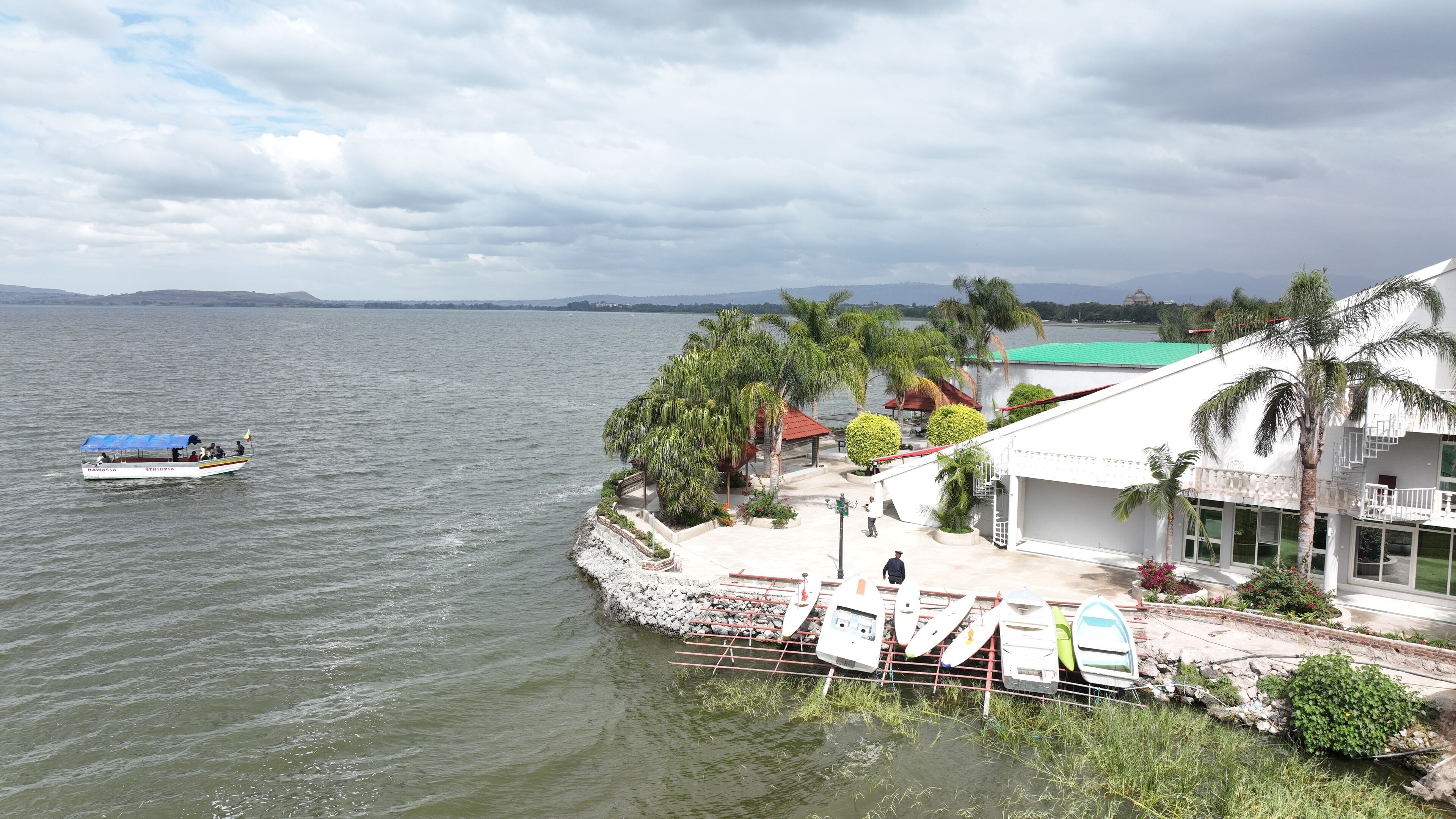 A waterfront property with a boat dock, a covered seating area, and a building with a green roof.