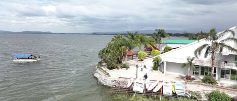 A waterfront property with a boat dock, a covered seating area, and a building with a green roof.