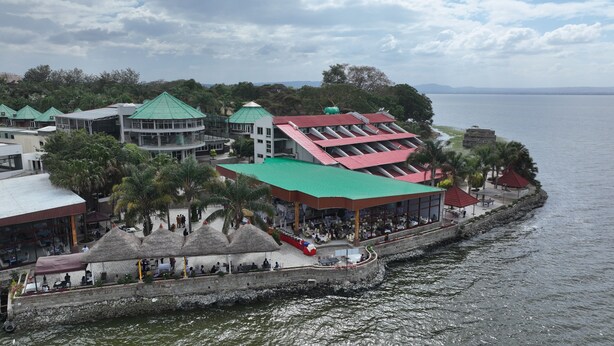 A coastal hotel with multiple dining areas, a stone waterfront promenade, and a view of the sea.